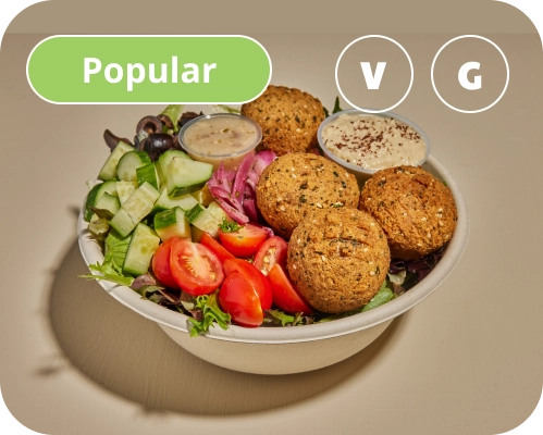 Falafel, sauces, and vegetables in a Mediterranean salad bowl.