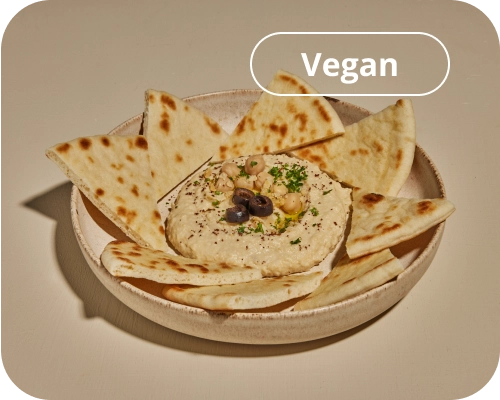 Plate with hummus in the center, surrounded by warm pita slices.