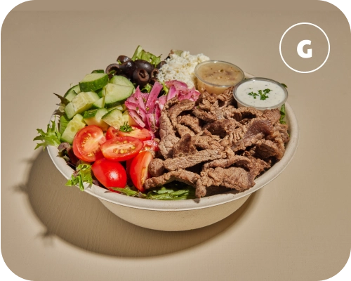 Steak shawarma, sauces, and vegetables in a Mediterranean salad bowl.